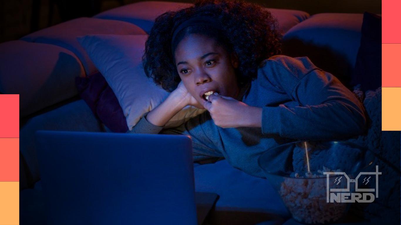 Pessoa assistindo série no computador com pipoca, simbolizando conforto ao rever histórias conhecidas