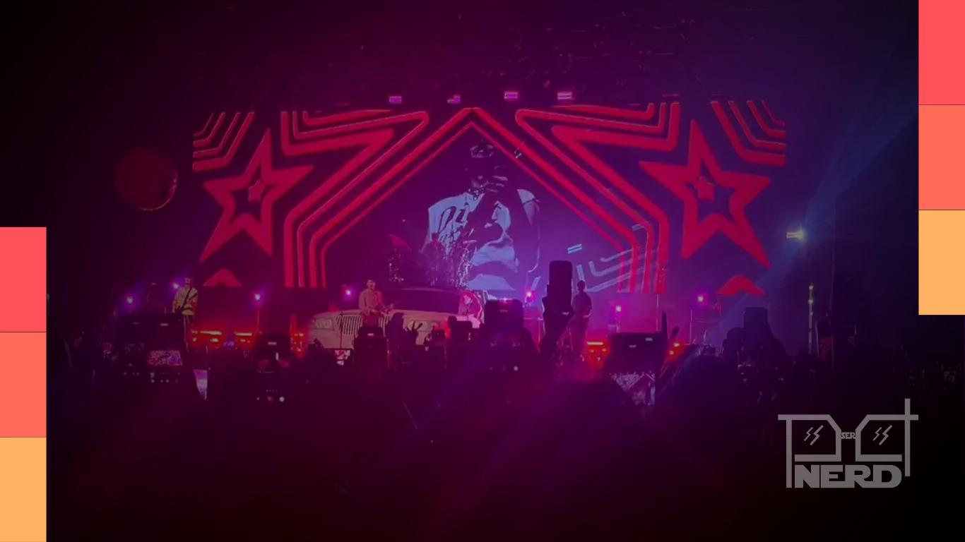 Banda 5 Seconds of Summer em palco durante show no Brasil com iluminação colorida e público pulando